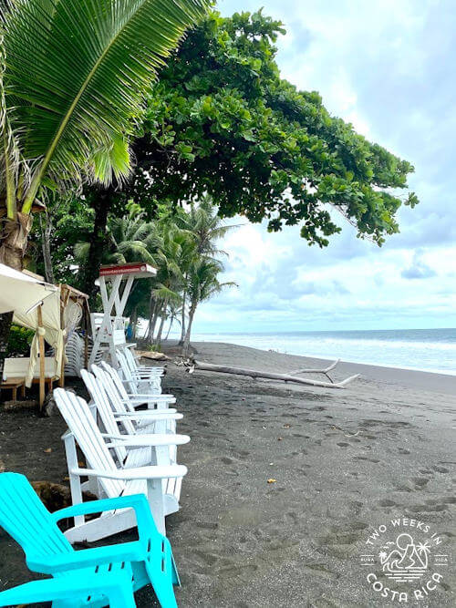 colorful chairs on black sand beach overlooking ocean