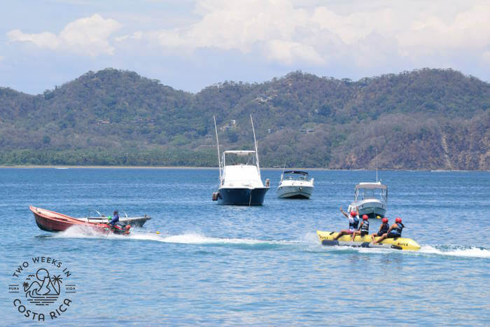 small motor boat pulling a banana boat raft with people on it