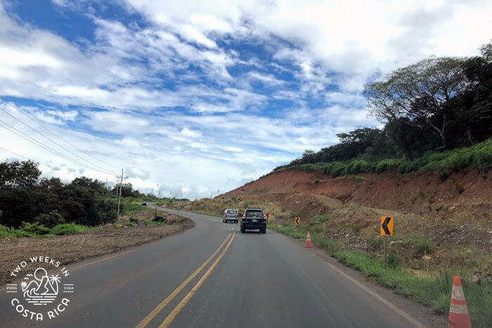 Paved highway road with yellow middle line and road cones at edges