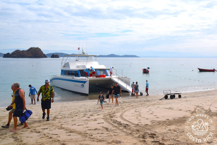 Catamaran boat pulled up onto sandy beach